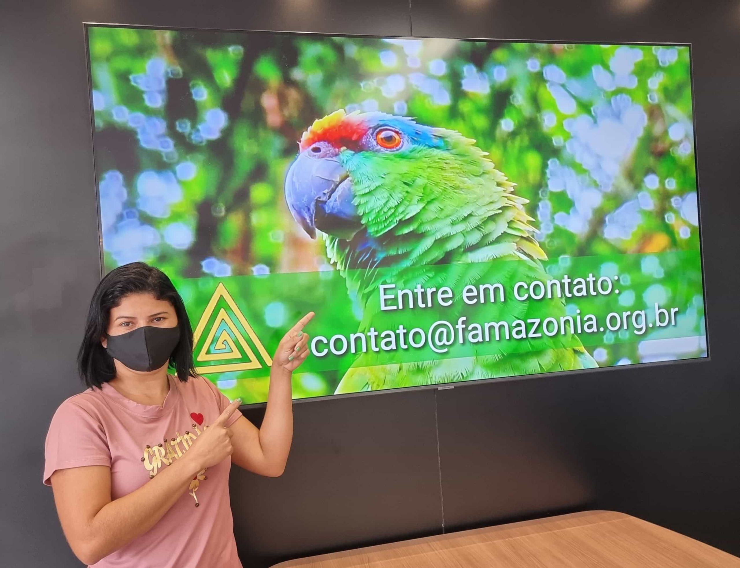 Imagem de mulher apontando para apresentação de slides que pede para entrar em contato com a FAMAZONIA
